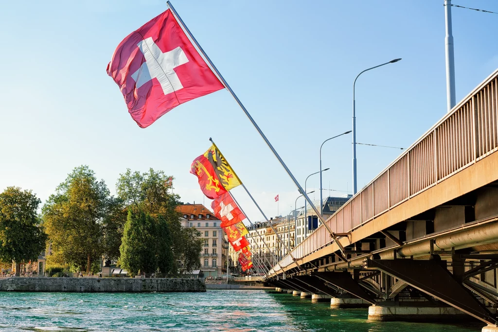 Photo d'un pont à Genève où l'on voit une succession de drapeaux suisses et du canton de Genève - NIMSuisse a un bureau à Genève